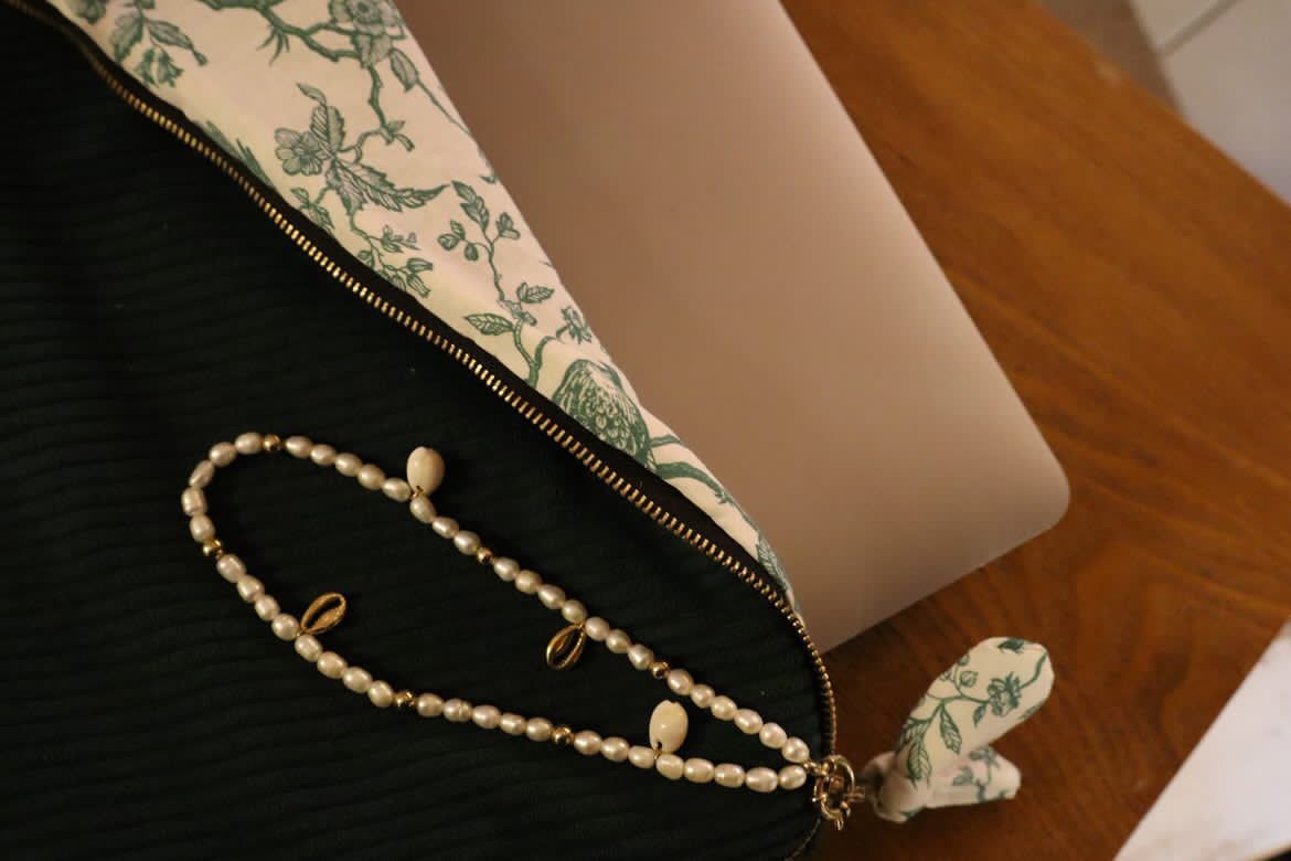 Pochette artisanale personnalisable en tissu vert avec doublure fleurie et bijou perlé