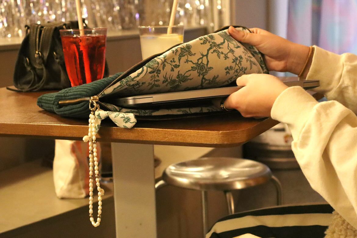 Pochette artisanale personnalisable contenant un ordinateur portable, avec doublure fleurie et bijou perlé